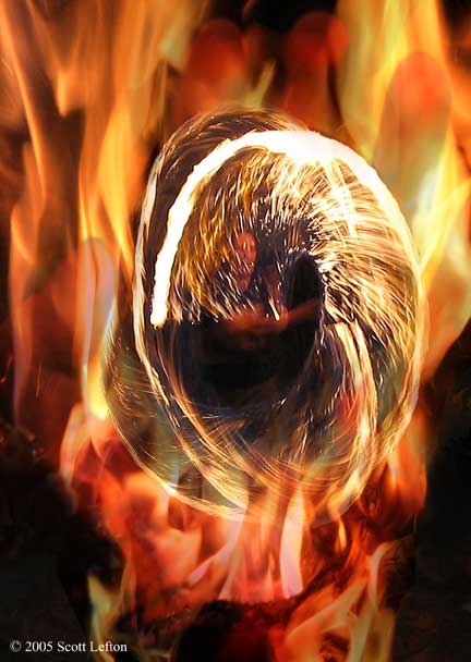 Fire - A hand engulfed in flames holds a man partially hidden behind a spiral of whirling sparks.
