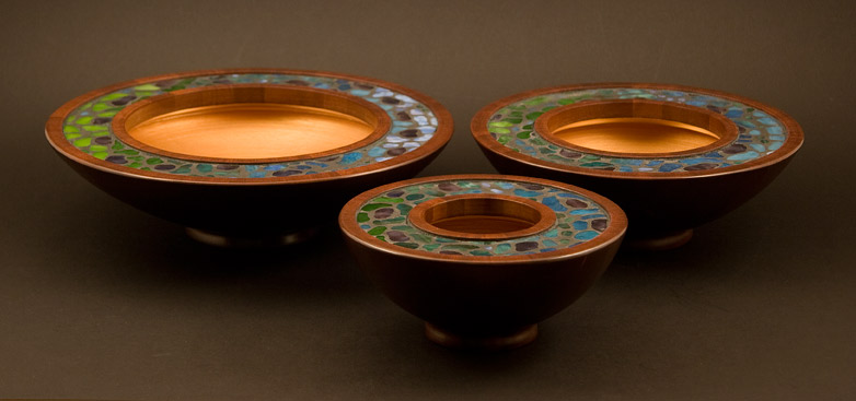 Side view of three mosaic bowls in dark reddish mahogany with green, blue and purple stained glass mosaic inlay, looking somewhat Tiffany.  The inside surfaces are finished in gold acrylic paiint.