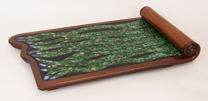 The Scroll Tray, with a mahogany frame and mostly green stained glass mosaic making a design of tentacles coming out from under the curved scroll.