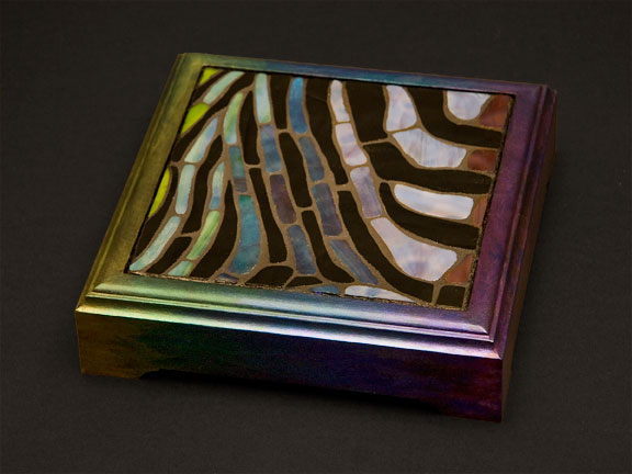 Stained glass mosaic trivet shading in greens, blues and purples, with painted frame.